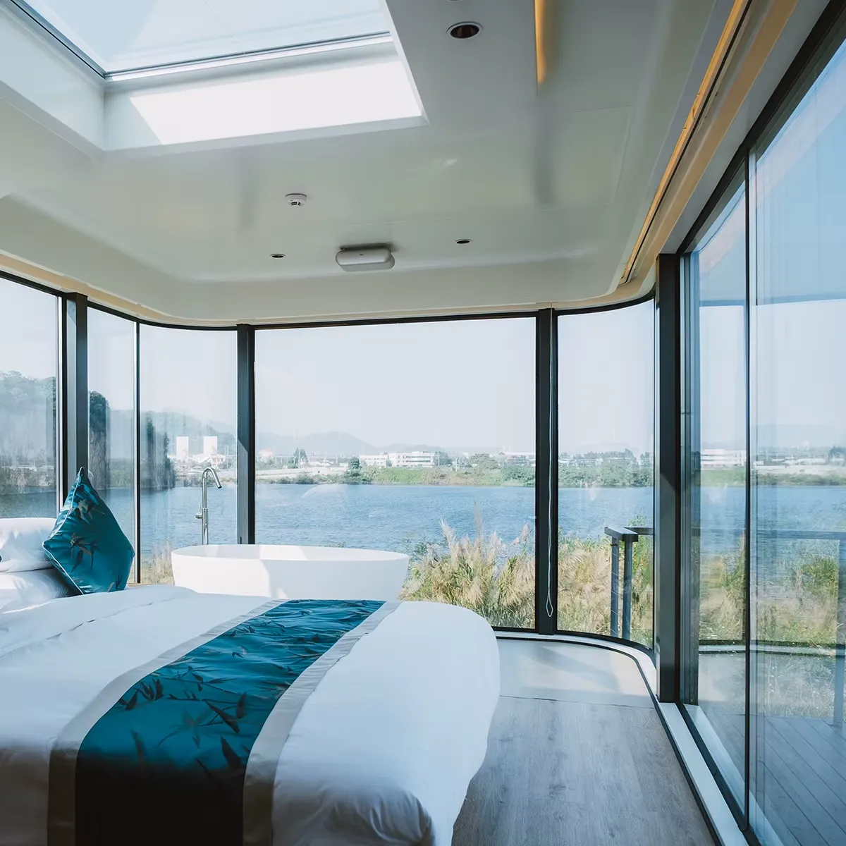 Dormitorio con cristaleras panorámicas frente a un lago al amanecer